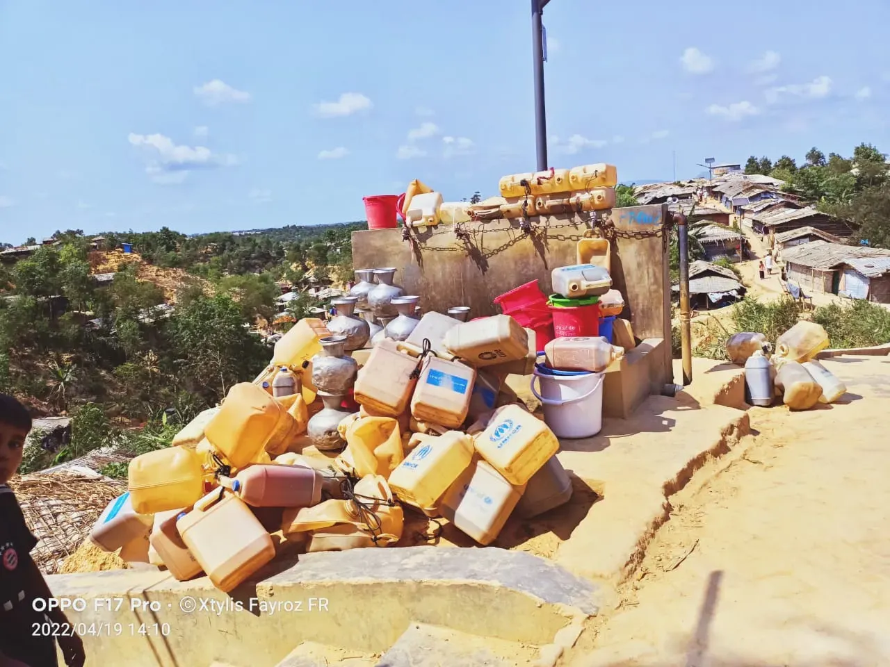 A pile of water containers lined up by an empty water point