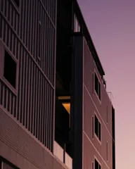 A dark grey building reflecting the violet wash of sunset